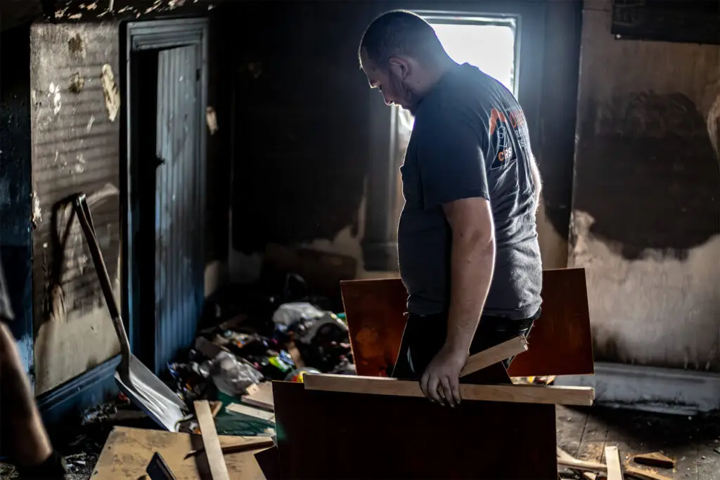 CRS employee standing in a room with a pile of debris